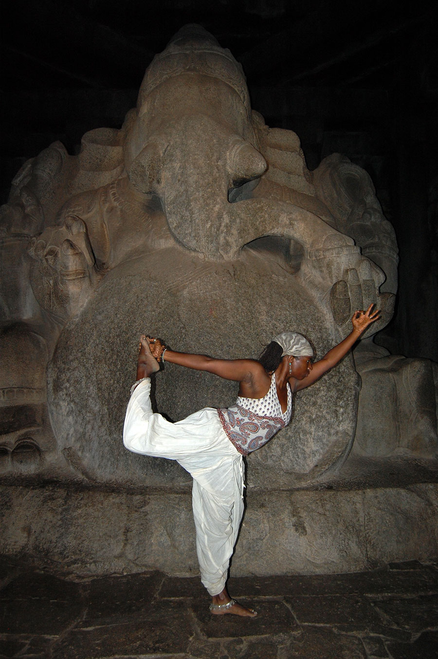A woman in white pants and top doing yoga.