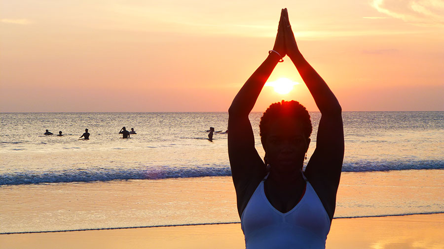 A woman is doing yoga on the beach