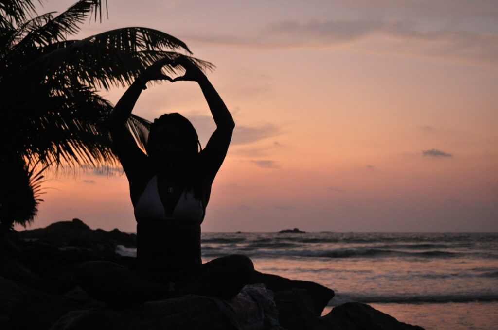 A woman sitting on top of rocks near the ocean.