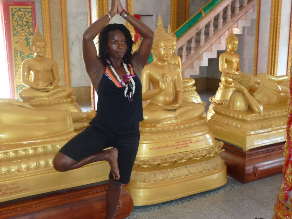 A woman is doing yoga in front of some statues.