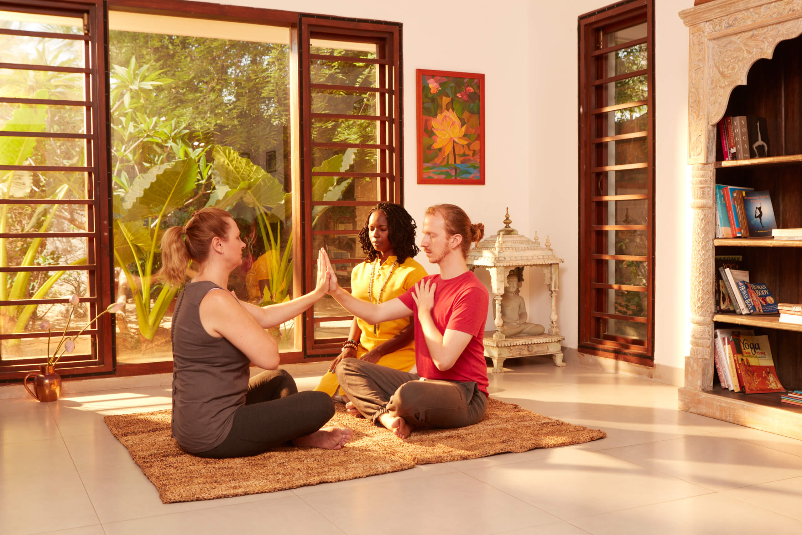 Three women sitting on a rug in front of windows.