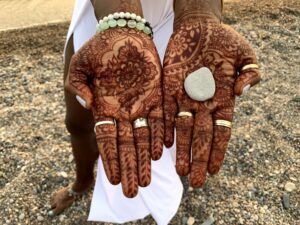 Henna-decorated hands holding a small stone.