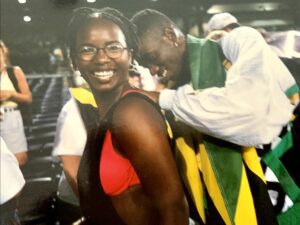 Smiling woman with Jamaican flag in background.