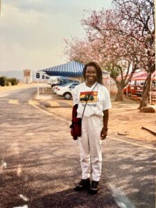 Woman standing near blooming trees and cars.