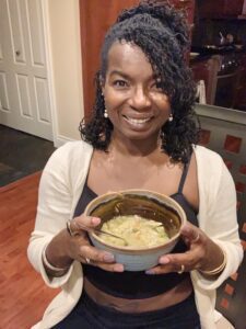 Smiling woman holding a bowl of soup.