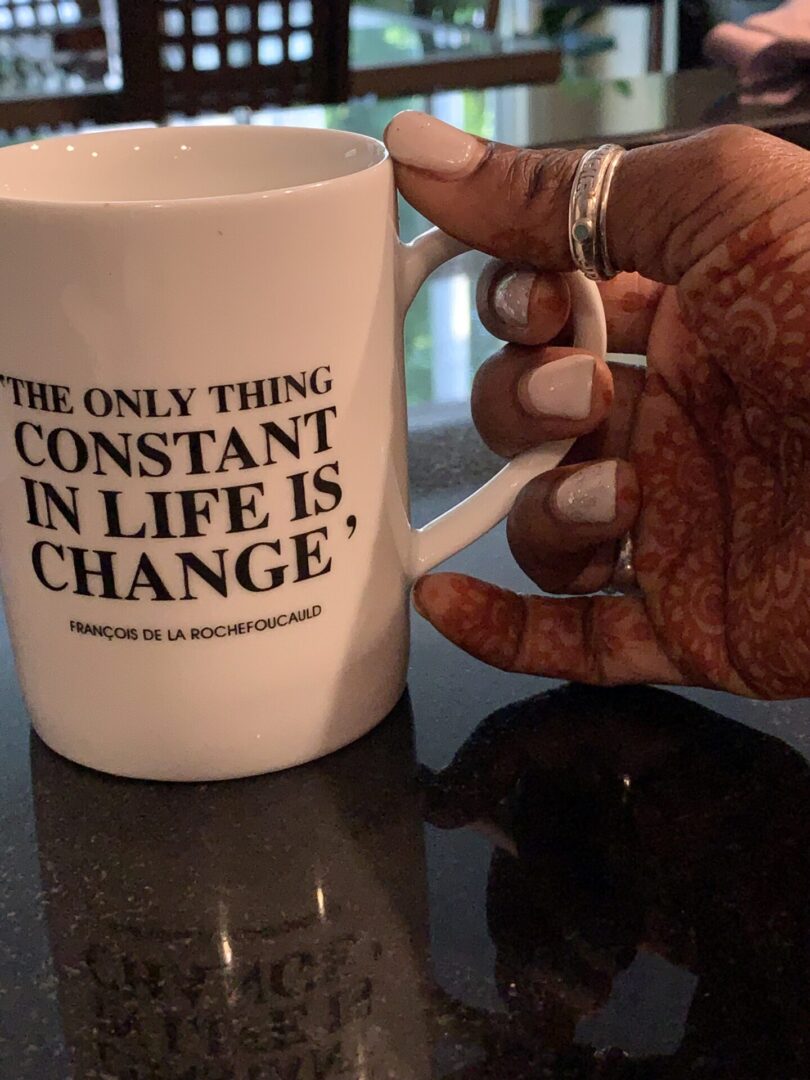 A person holding onto a coffee mug with the words " constant in life is change ".