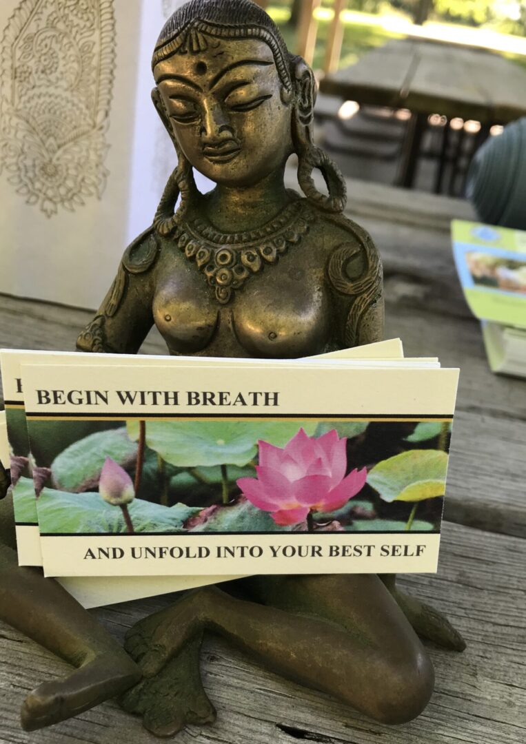 A statue of a woman holding a card with the words " begin with breath and unfold into your best self ".
