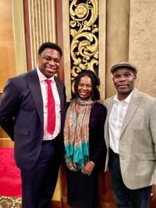 Three people posing indoors, smiling warmly.